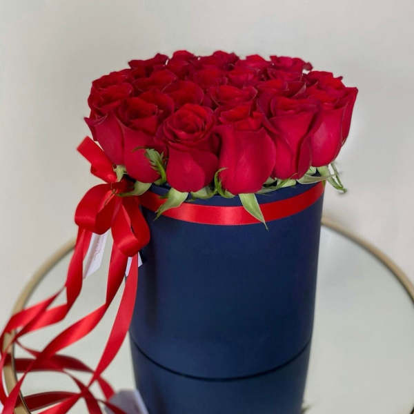 Red roses arranged in a navy round box with a red ribbon