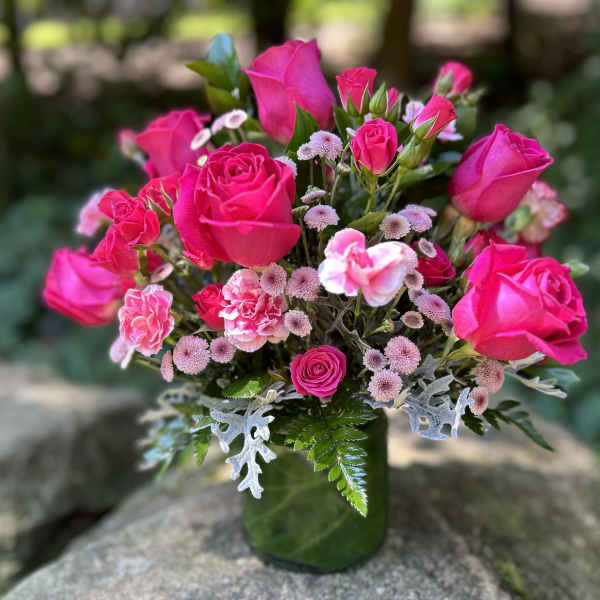 Pink roses and small pink flowers in a green glass vase