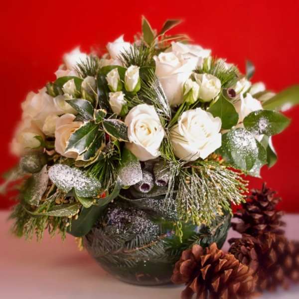 White rose bouquet in a dark glass vase with pinecones