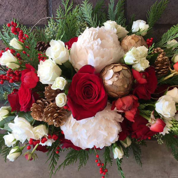 Red and white floral arrangement with pinecones and berries