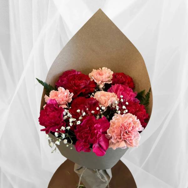 Bouquet of red and pink carnations wrapped in brown paper