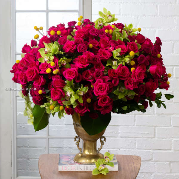 Large bouquet of hot pink roses and green orchids in a gold vase