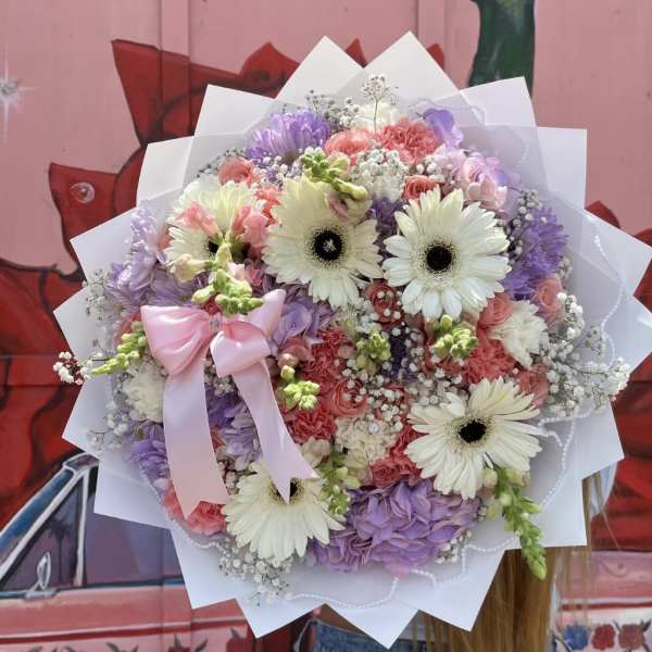 Round bouquet of pastel flowers with a pink ribbon