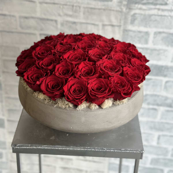 Round arrangement of red roses in a low gray bowl