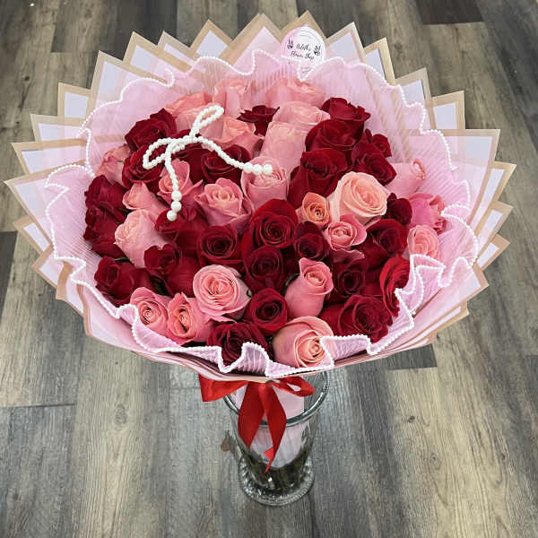 Bouquet of red and pink roses in pink wrapping with a glass vase
