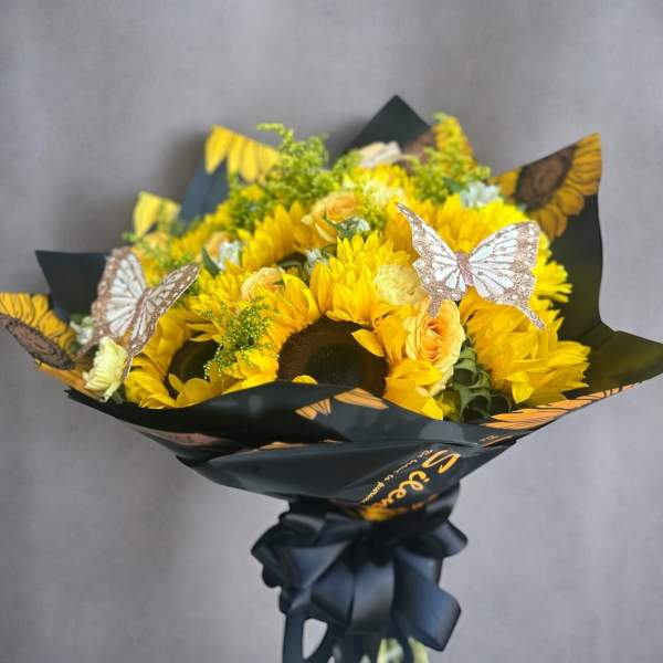 Bouquet of yellow sunflowers with butterfly decorations in black wrap