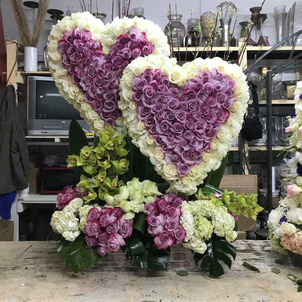 Two large heart-shaped rose arrangements in purple and white