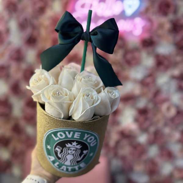 White roses in a gold cup with a black bow