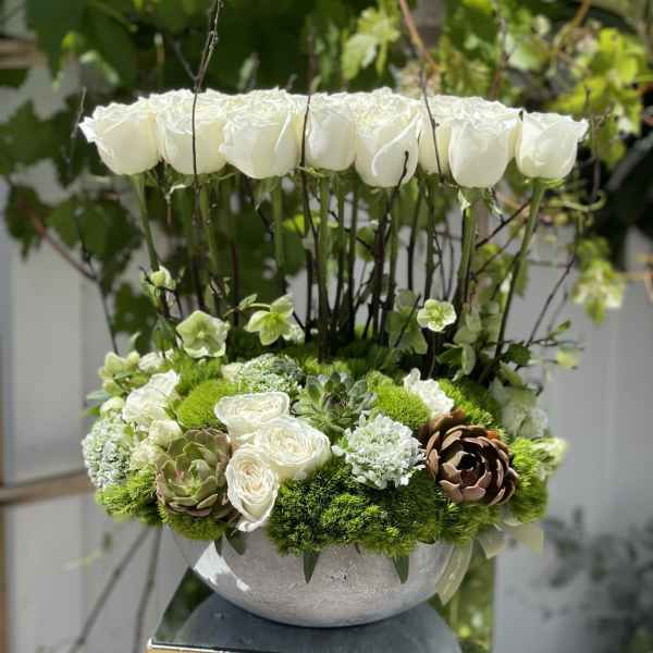 White roses and green succulents in a round gray vase