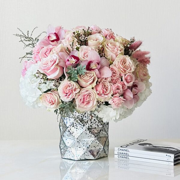 Pink rose bouquet in a faceted mirrored vase with a Chanel book stack nearby