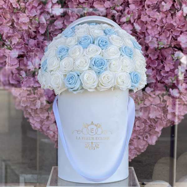 White and blue roses in a white hatbox with ribbon handles