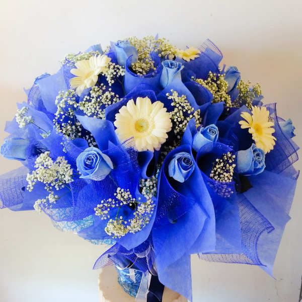 Blue bouquet with white daisies and small filler flowers in a vase