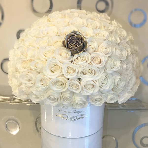Round hatbox arrangement of many ivory roses with a single metallic gold rose accent.