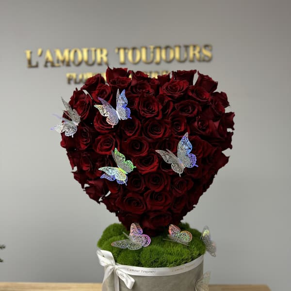 Heart-shaped bouquet of red roses in a gray box with butterfly decorations