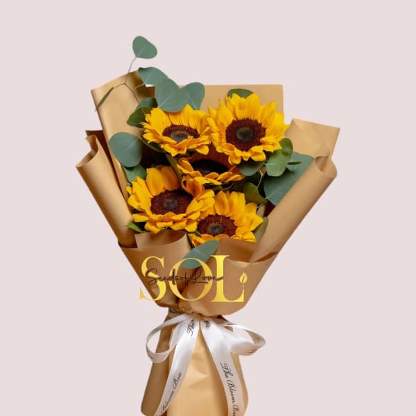 Bouquet of yellow sunflowers wrapped in brown paper with a white ribbon