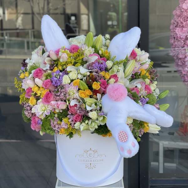 Large mixed flower arrangement in a white box with a plush bunny