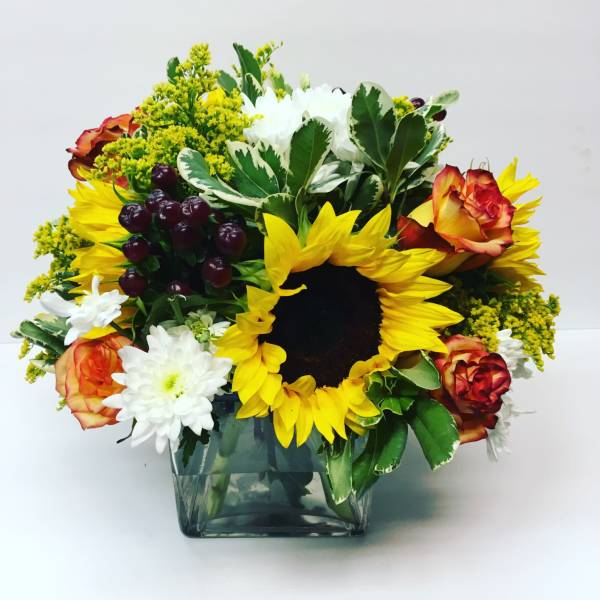 Sunflower and rose bouquet in a square glass vase