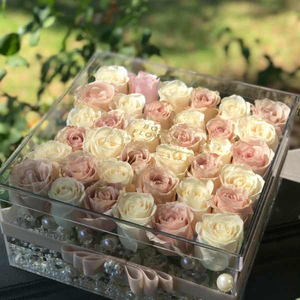 Box of blush and cream roses with a clear lid and ribbon trim