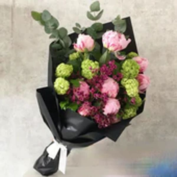 Bouquet of pink and green flowers wrapped in black paper
