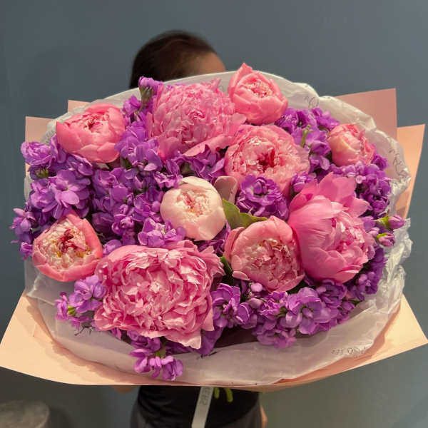 Bouquet of pink peonies and purple flowers wrapped in paper
