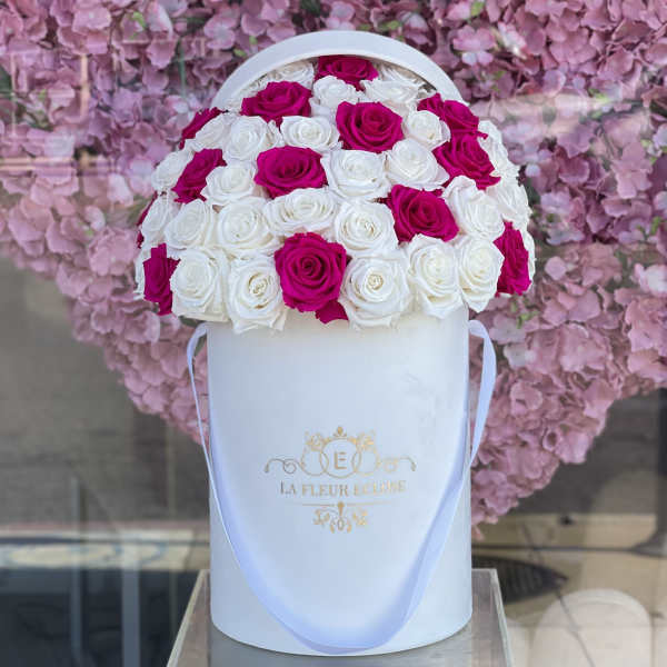 Pink and white roses arranged in a white hat box