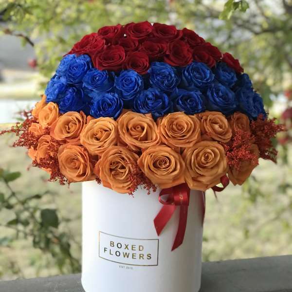 Red, blue, and orange roses arranged in a white hat box
