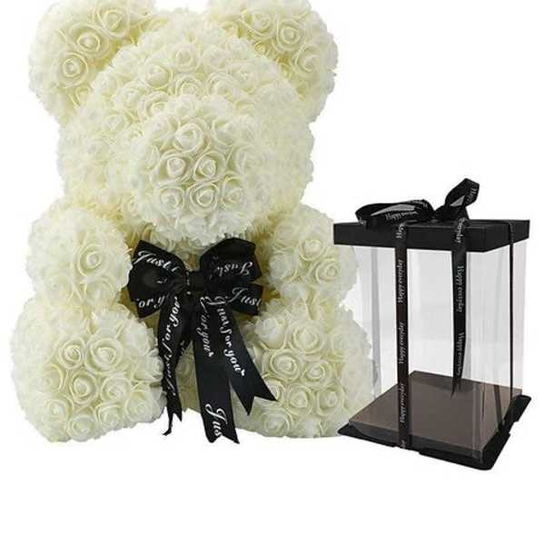 White rose teddy bear with a black ribbon beside a clear gift box