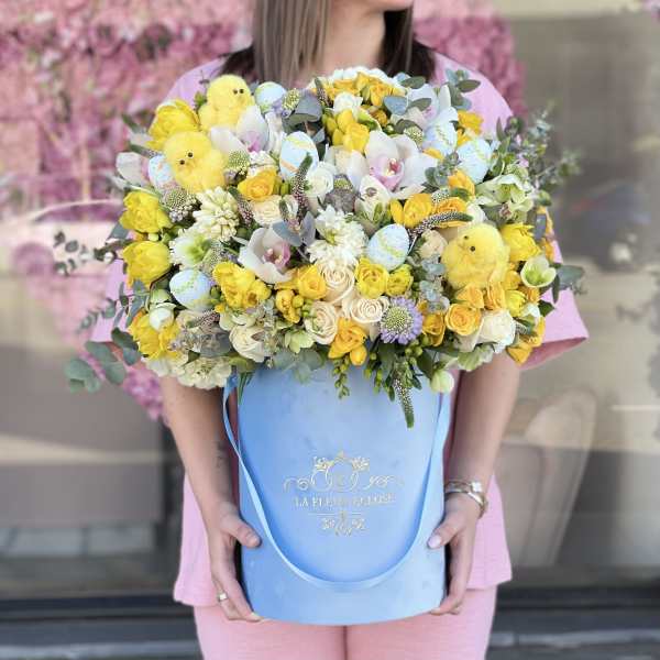 Large bouquet of yellow and white flowers in a blue hatbox with chick decorations