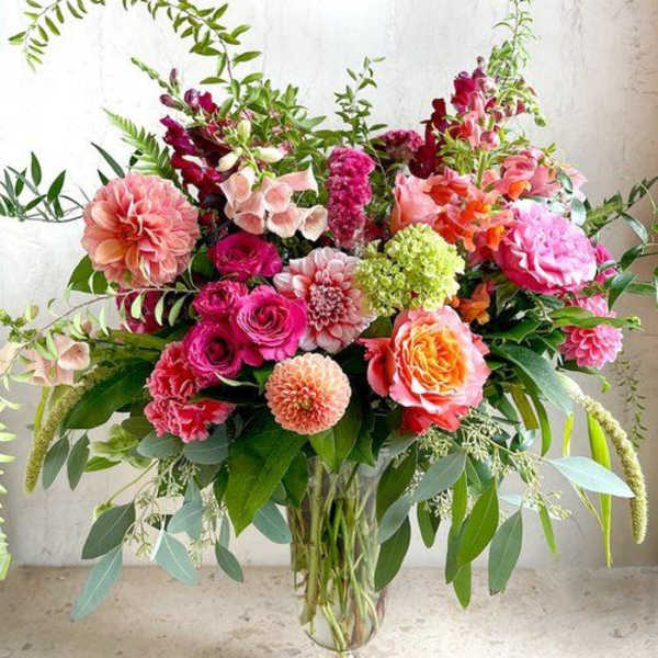 Large mixed bouquet of pink, peach, and orange flowers in a glass vase