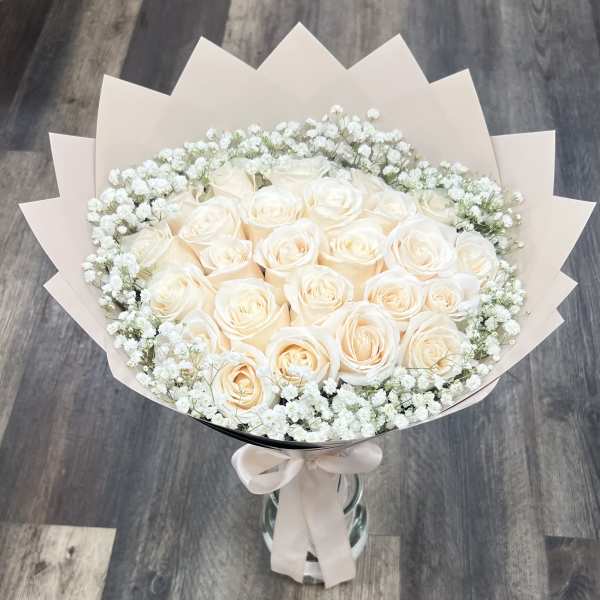 Bouquet of cream roses with white baby's breath in pale wrapping