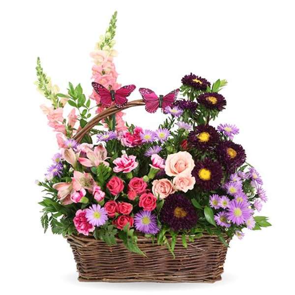 Basket arrangement of pink and purple flowers with butterfly picks