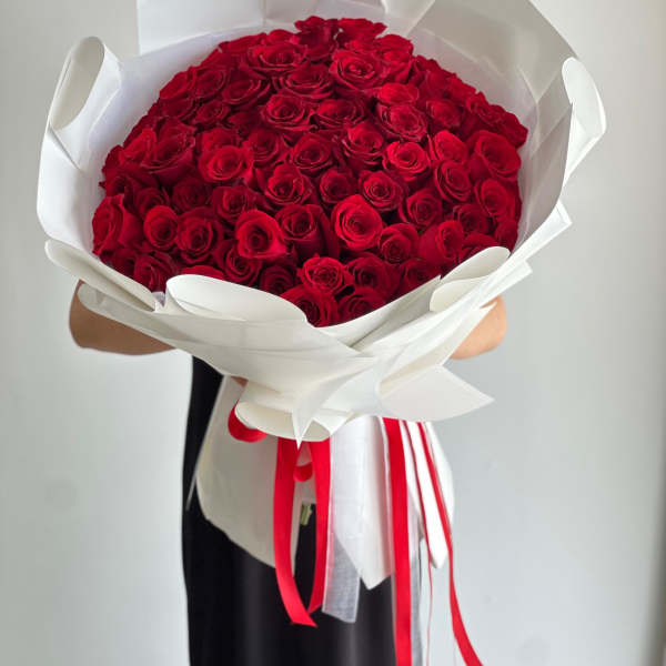 Large bouquet of red roses wrapped in white paper with red ribbons