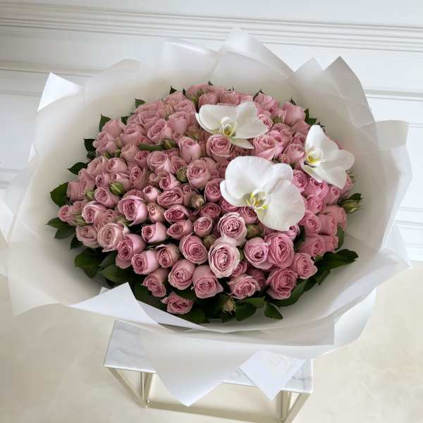 Large bouquet of pink roses with white orchids wrapped in white paper