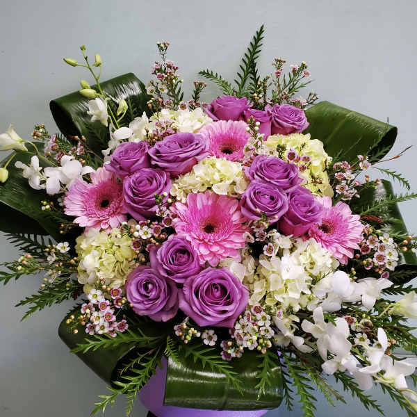 Bouquet of purple roses, pink gerberas, and white orchids