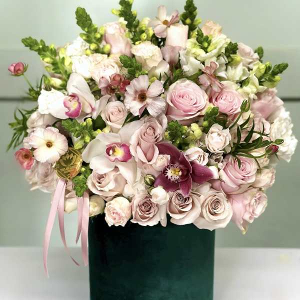 Pink and white floral arrangement in a dark green box with ribbon