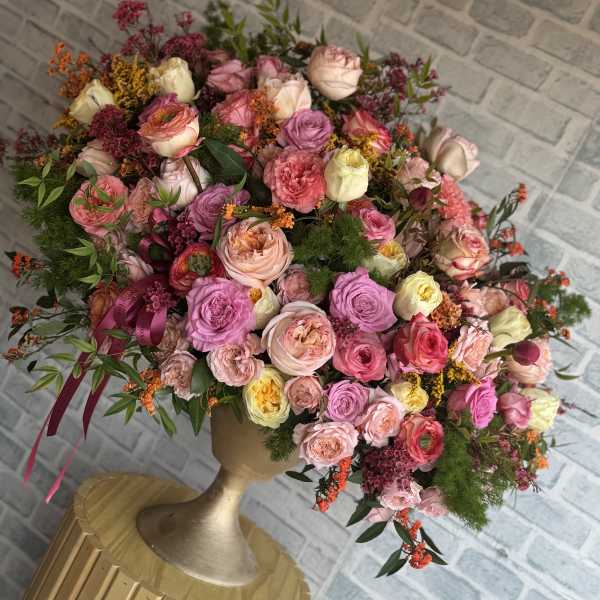 Large bouquet of pink and cream roses in a gold vase