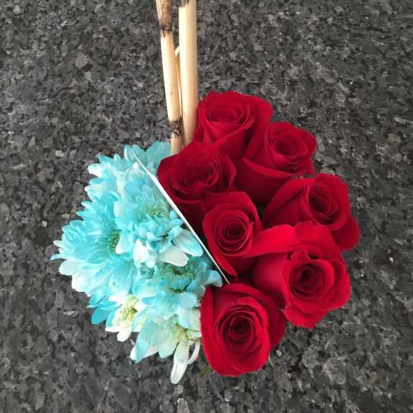 Red roses and blue daisies arranged with bamboo sticks