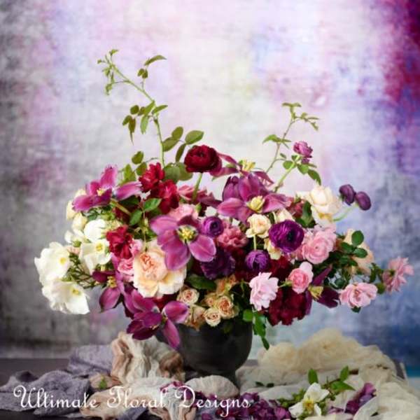 Mixed pink, purple, and white flowers arranged in a black vase