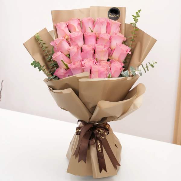 Bouquet of pink roses wrapped in brown paper with a ribbon