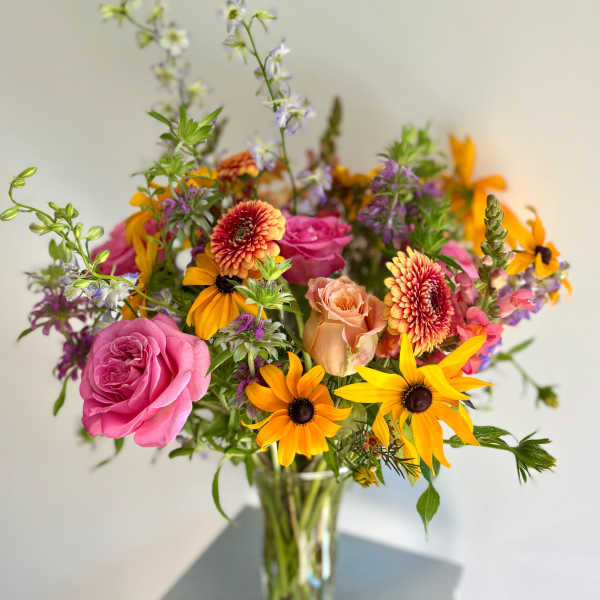 Mixed bouquet of pink roses and orange daisies in a glass vase
