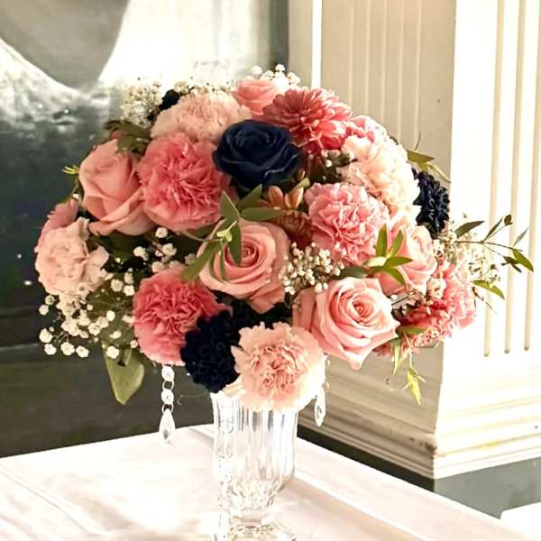 Pink and coral bouquet with roses and carnations in a clear glass vase