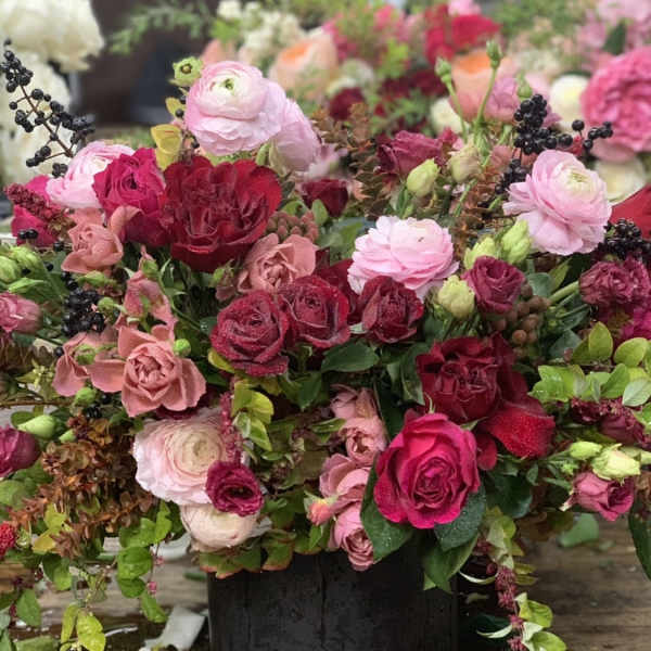 Mixed pink and red flower arrangement in a black container
