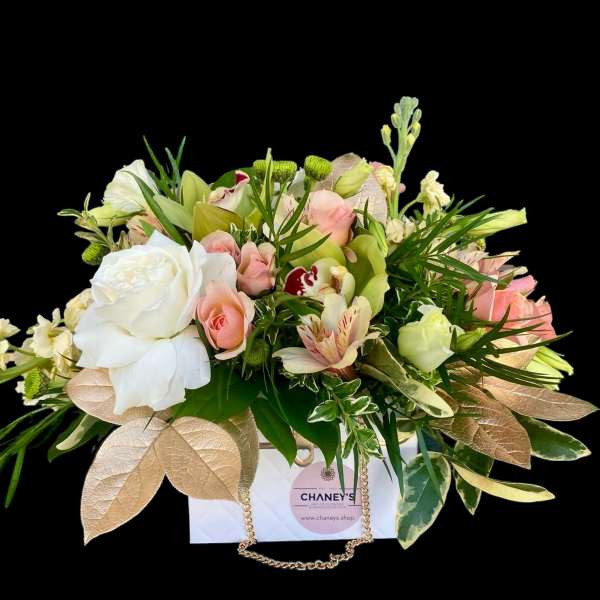 Mixed bouquet of white and pink flowers in a white gift bag