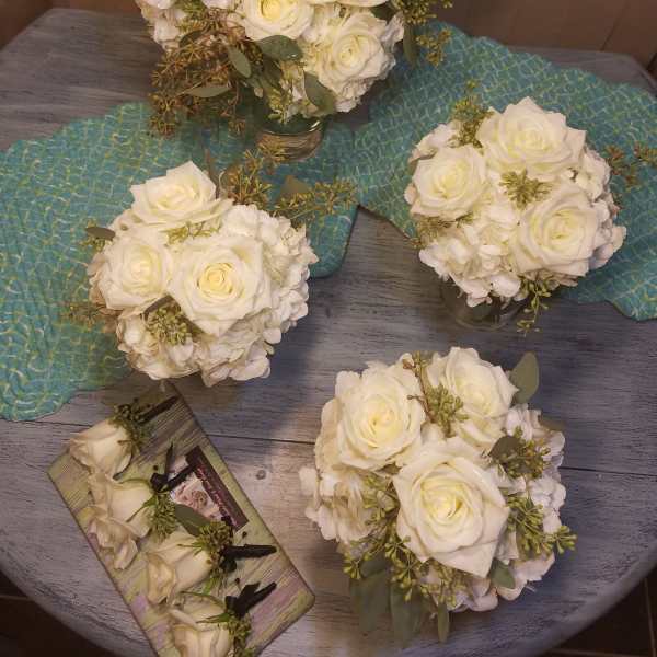 White rose bouquets with hydrangea and greenery on a table