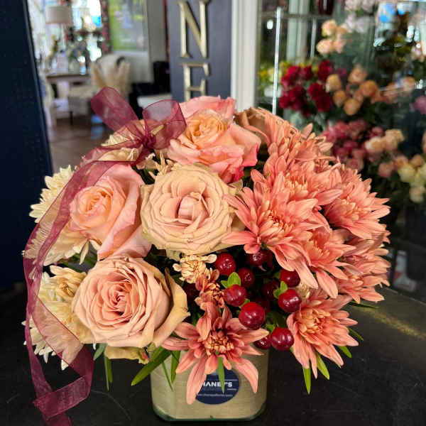 Peach roses and coral chrysanthemums in a square vase with burgundy ribbon