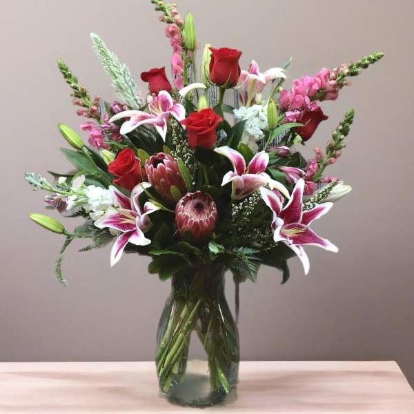 Mixed bouquet of red roses and pink lilies in a glass vase