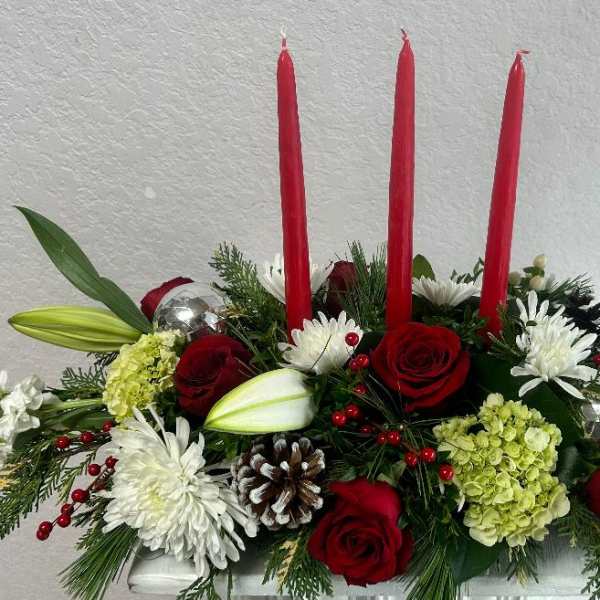 Red candles in a floral centerpiece with roses, lilies, and white blooms