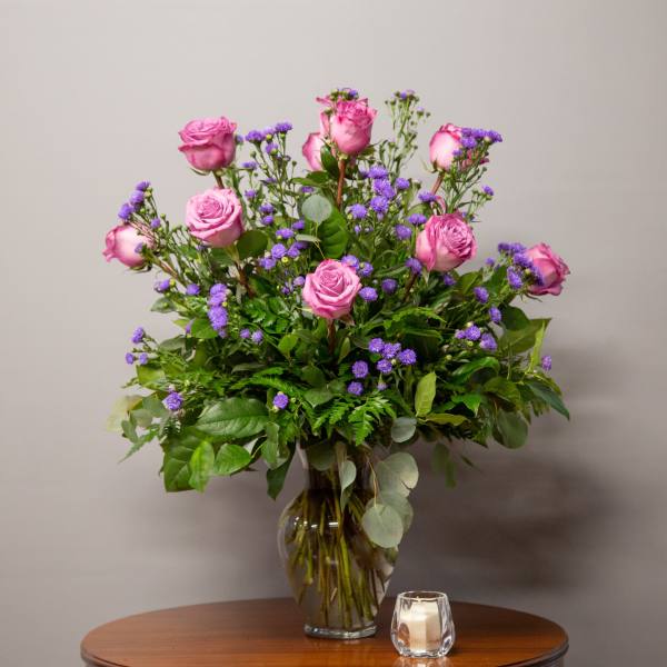 Pink roses and purple filler flowers in a glass vase