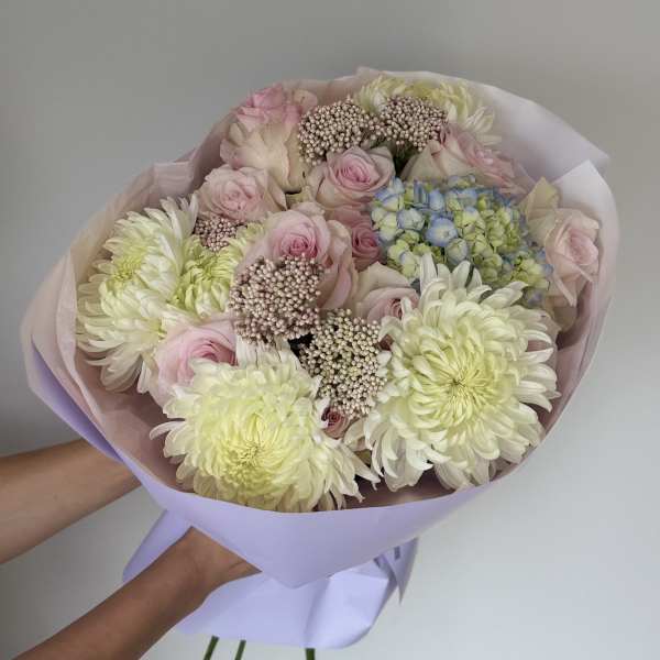 Bouquet of pale pink roses and cream chrysanthemums wrapped in lavender paper