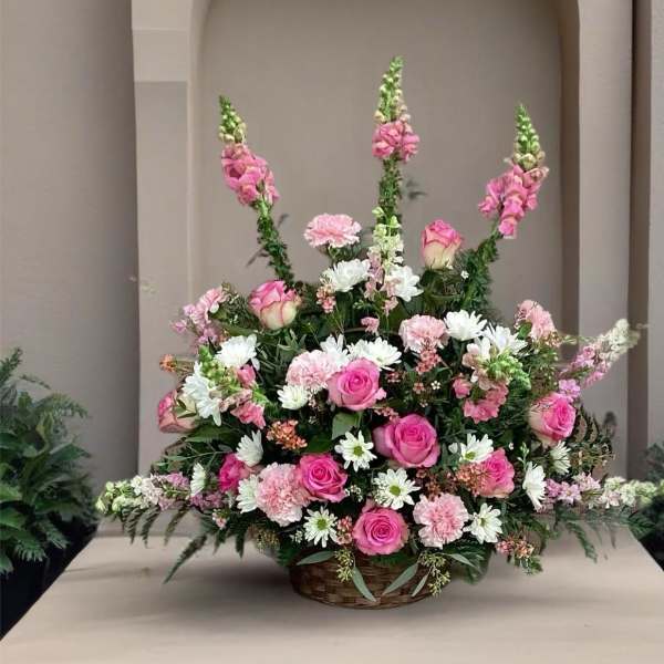 Large basket arrangement of pink roses, carnations, and white daisies